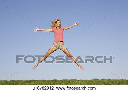 Young woman jumping in air View Large Photo Image Stock Image - Young woman jumping in air. Fotosearch