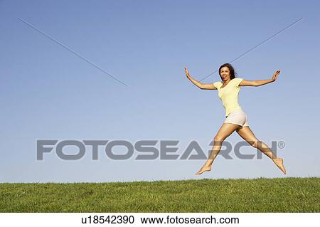 Young woman jumping in air View Large Photo Image Stock Image - Young woman jumping in air. Fotosearch