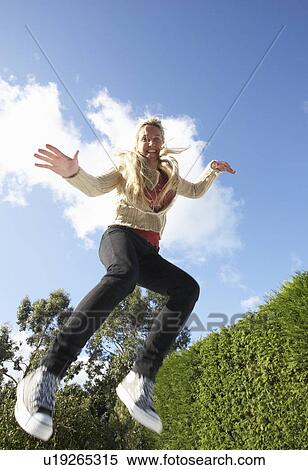 Young Woman Jumping On Trampoline Caught In Mid Air View Large Photo Image Stock Photography - Young Woman Jumping On Trampoline Caught In Mid Air. Fotosearch