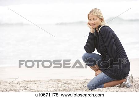 Young Woman On Holiday Kneeling On Winter Beach View Large Photo Image Stock Photo - Young Woman On Holiday Kneeling On Winter Beach. Fotosearch
