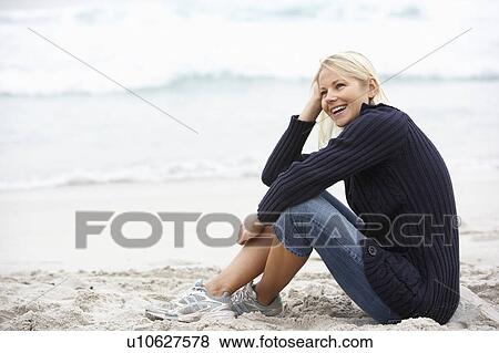 Stock Photo - Young Woman On Holiday Sitting On Winter Beach. Fotosearch