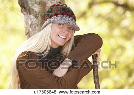 Stock Photo - Young Woman Outdoors Walking In Autumn Woodland Holding Walking Stick. Fotosearch