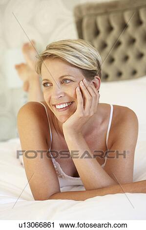 Stock Image - Young Woman Relaxing In Bedroom. Fotosearch