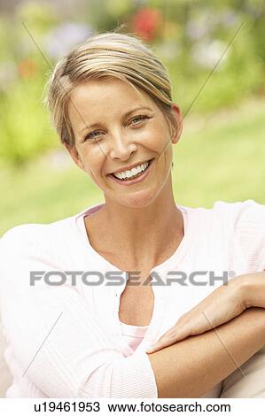 Stock Image - Young Woman Relaxing In Garden. Fotosearch