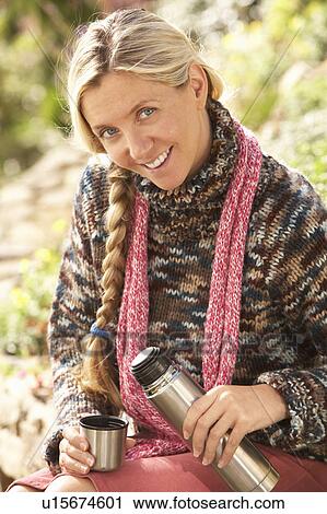 Stock Image - Young Woman Relaxing With Thermos Flask In Autumn Landscape. Fotosearch