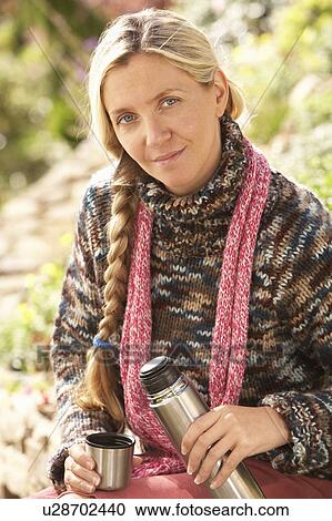 Stock Image - Young Woman Relaxing With Thermos Flask In Autumn Landscape. Fotosearch
