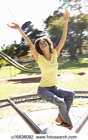 Stock Image - Young Woman Riding On Roundabout In Park. Fotosearch