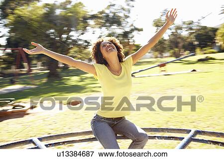 Stock Photo - Young Woman Riding On Roundabout In Park. Fotosearch