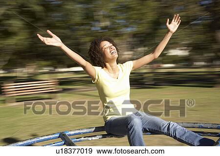 Stock Photo - Young Woman Riding On Roundabout In Park. Fotosearch