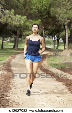 Young woman running in park View Large Photo Image Stock Image - Young woman running in park. Fotosearch