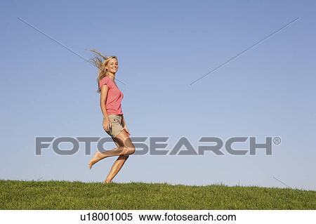 Young woman running through field View Large Photo Image Stock Photography - Young woman running through field. Fotosearch