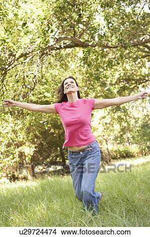 Picture - Young Woman Running Through Long Grass In Park. Fotosearch