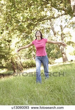 Stock Image - Young Woman Running Through Long Grass In Park. Fotosearch