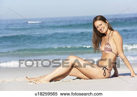 Young Woman Sitting On Sandy Beach On Holiday Wearing Bikini View Large Photo Image Stock Photography - Young Woman Sitting On Sandy Beach On Holiday Wearing Bikini. Fotosearch