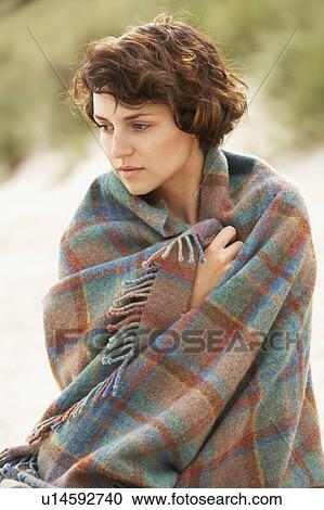 Stock Image - Young Woman Standing In Sand Dunes Wrapped In Blanket. Fotosearch