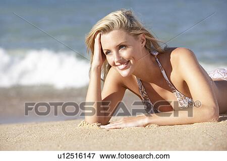 Stock Photo - Young Woman Sunbathing On Beach . Fotosearch