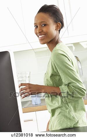 Stock Photo - Young Woman Using Computer In Modern Kitchen . Fotosearch