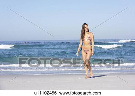 Young Woman Walking Along Sandy Beach On Holiday Wearing Bikini View Large Photo Image Stock Photograph - Young Woman Walking Along Sandy Beach On Holiday Wearing Bikini. Fotosearch