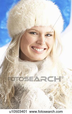 Stock Image - Young Woman Wearing Warm Winter Clothes And Fur Hat In Studio. Fotosearch