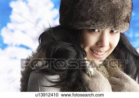 Stock Image - Young Woman Wearing Warm Winter Clothes And Fur Hat In Studio. Fotosearch
