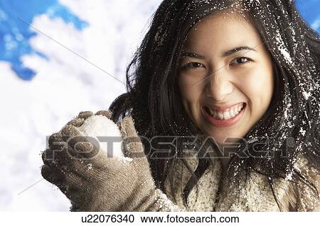 Stock Image - Young Woman Wearing Warm Winter Clothes Holding Snowball In Studio. Fotosearch
