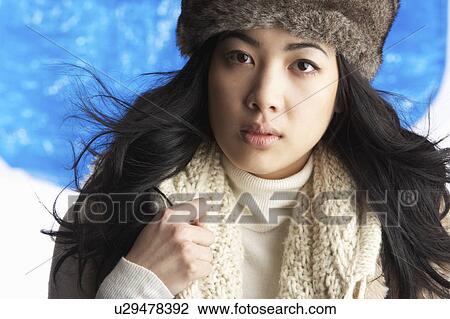 Stock Image - Young Woman Wearing Warm Winter Clothes And Fur Hat In Studio. Fotosearch