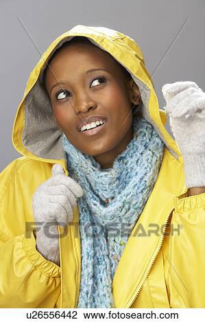 Stock Image - Young Woman Wearing Yellow Raincoat In Studio. Fotosearch