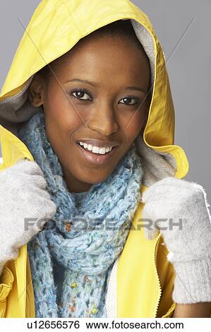 Stock Photograph - Young Woman Wearing Yellow Raincoat In Studio. Fotosearch