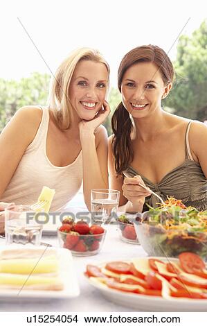 Picture - Young women eating outdoors. Fotosearch