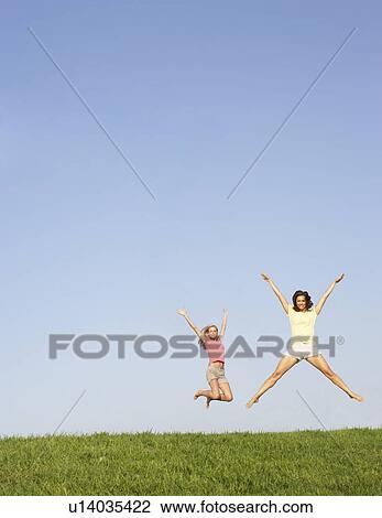 Stock Image - Young women jumping in air. Fotosearch