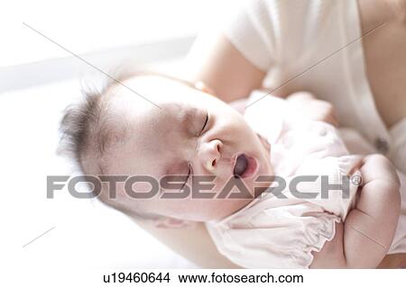 Picture - Baby girl yawning in mother's arms. Fotosearch