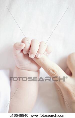 Stock Image - Baby holding mother's finger. Fotosearch