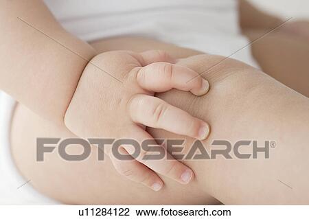 Stock Image - Baby's hand touching thigh. Fotosearch