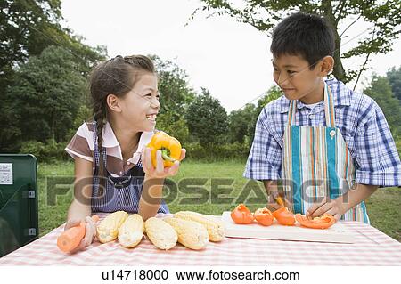 Stock Image - Boy and girl chopping orange bell pepper, Chiba Prefecture, Honshu, Japan. Fotosearch