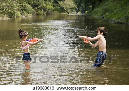 Stock Image - Boy and girl having water gun fight, Chiba Prefecture, Honshu, Japan. Fotosearch