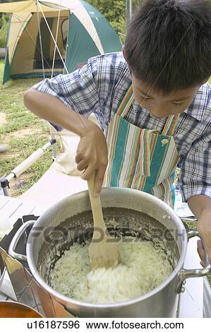 Stock Photograph - Boy Cooking at Campsite. Fotosearch