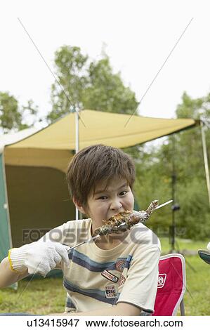 Stock Photo - Boy Eating Barbecued Fish From Skewer. Fotosearch