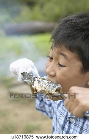 Stock Photography - Boy Eating Barbecued Fish. Fotosearch