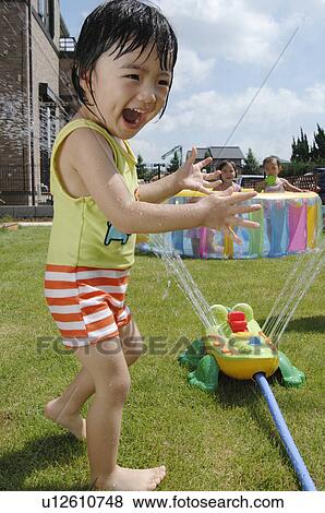 Boy getting wet by sprinkler, Chiba Prefecture, Honshu, Japan View Large Photo Image Stock Photo - Boy getting wet by sprinkler, Chiba Prefecture, Honshu, Japan. Fotosearch