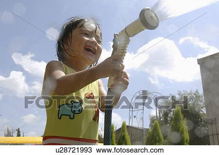 Stock Image - Boy playing with garden hose, Chiba Prefecture, Honshu, Japan. Fotosearch