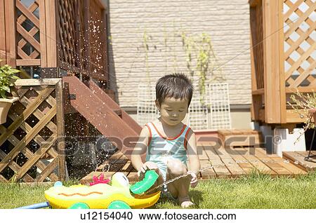 Stock Image - Boy playing with sprinkler, Chiba Prefecture, Honshu, Japan. Fotosearch