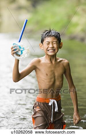 Stock Photo - Boy standing in river holding snorkel, Chiba Prefecture, Honshu, Japan. Fotosearch