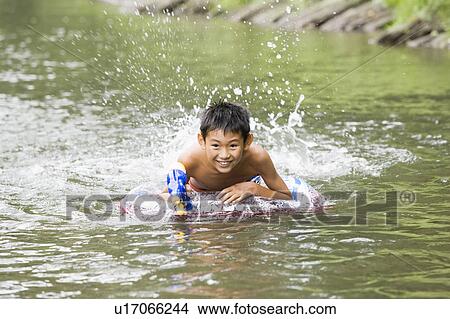Boy swimming in river holding a water gun, Chiba Prefecture, Honshu, Japan View Large Photo Image Picture - Boy swimming in river holding a water gun, Chiba Prefecture, Honshu, Japan. Fotosearch