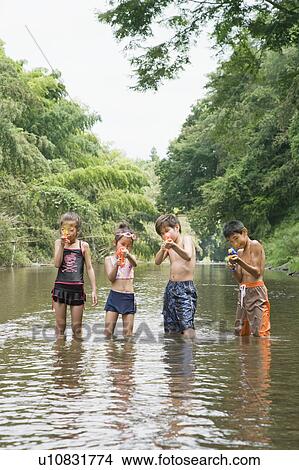 Picture - Boys and girls in river holding water guns, Chiba Prefecture, Honshu, Japan. Fotosearch