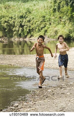 Stock Photo - Boys running by river, Chiba Prefecture, Honshu, Japan. Fotosearch