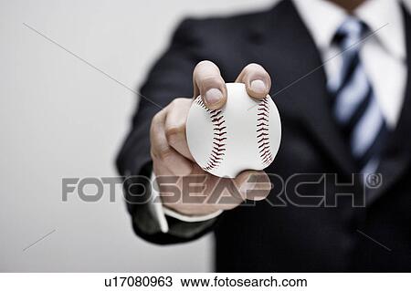 Stock Image - Businessman holding a baseball. Fotosearch