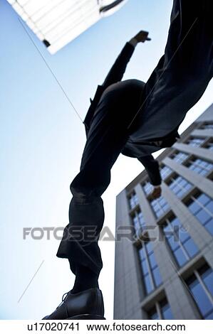 Stock Image - Businessman jumping, low angle view. Fotosearch