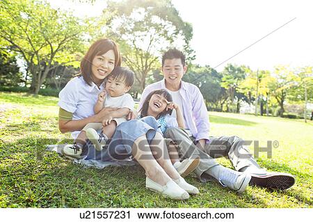 Stock Image - Family sitting on grass. Fotosearch
