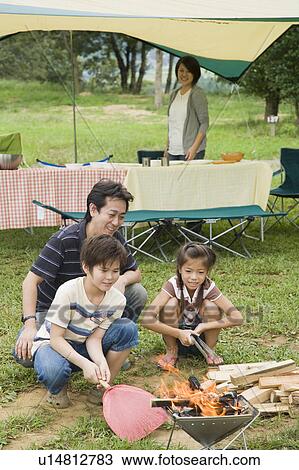 Stock Image - Family starting a campfire, Chiba Prefecture, Honshu, Japan. Fotosearch