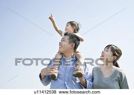 Stock Photo - Father carrying daughter on shoulder looking up. Fotosearch